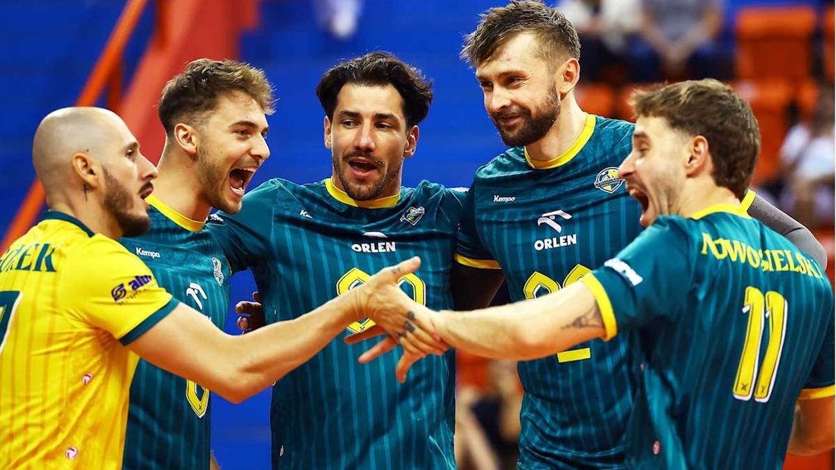 Pięciu siatkarzy w zielonych koszulkach świętuje zwycięstwo, podając sobie ręce.