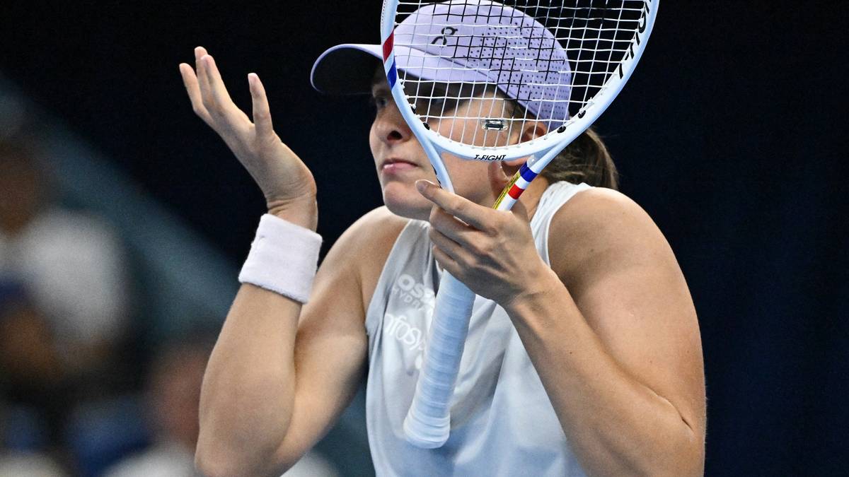 Tenisistka Iga Świątek z białą czapką i rakietą w dłoni, wyraża frustrację po porażce.