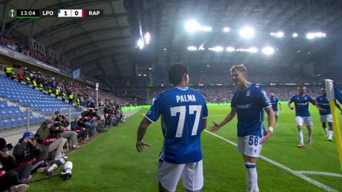 Dw&oacute;ch piłkarzy Lecha Poznań w niebieskich koszulkach świętuje na boisku, jeden z nich ma numer 77 na plecach.