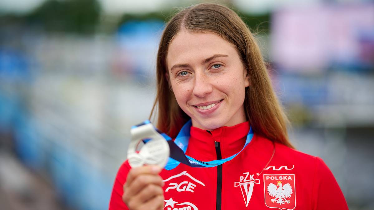 Kobieta w czerwonej bluzie trzymająca srebrny medal.