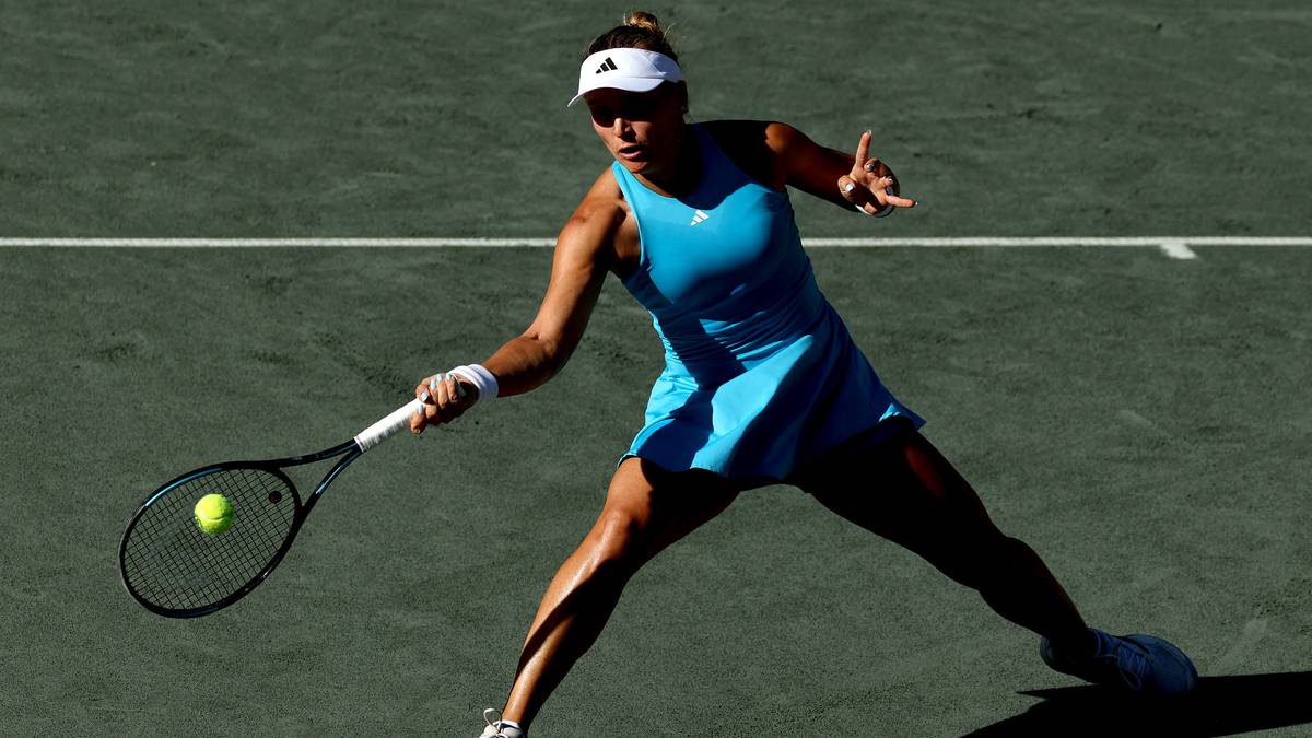 Tenisistka w niebieskiej sukience wykonuje forhendowe uderzenie na korcie tenisowym.