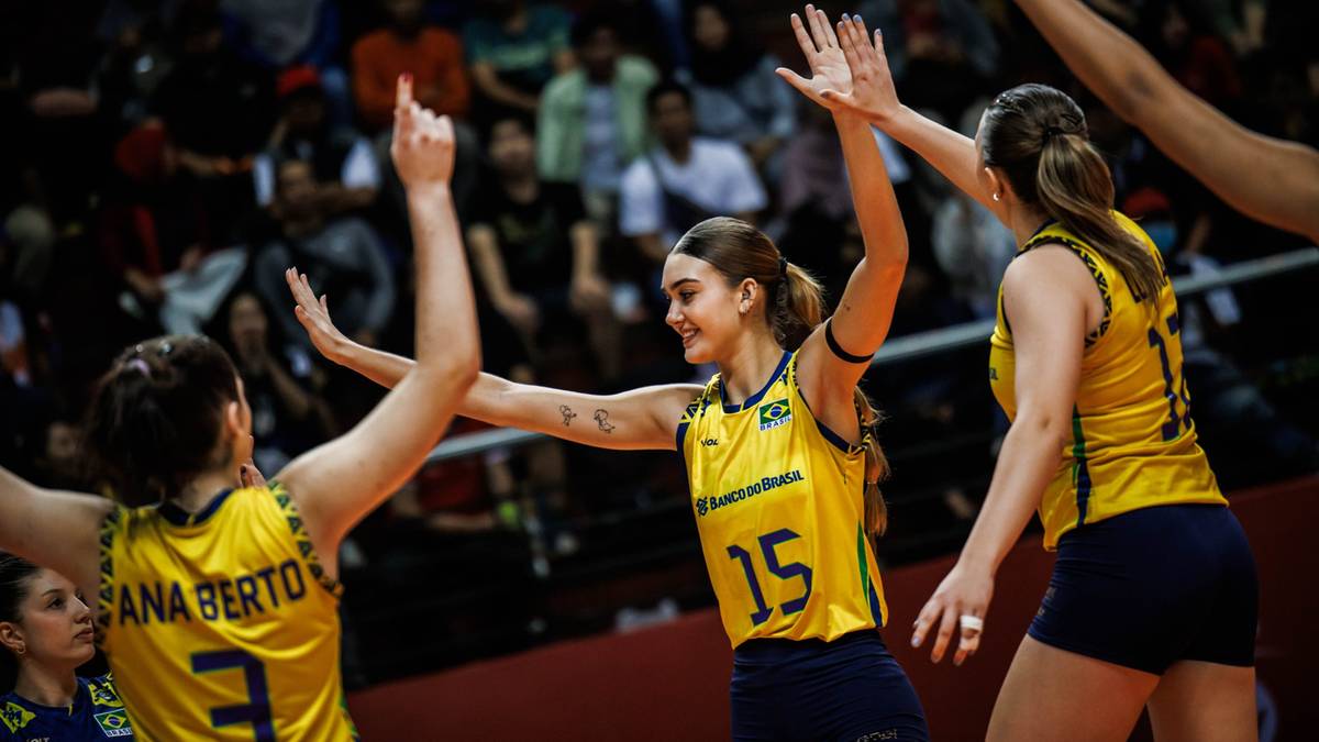 Trzy siatkarki w ż&oacute;łtych koszulkach z numerami na plecach świętują zdobycie punktu, wznosząc ręce w g&oacute;rę.