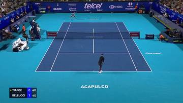 Frances Tiafoe serwuje podczas meczu tenisa z Mattia Belluccim. Wynik meczu widoczny na ekranie.