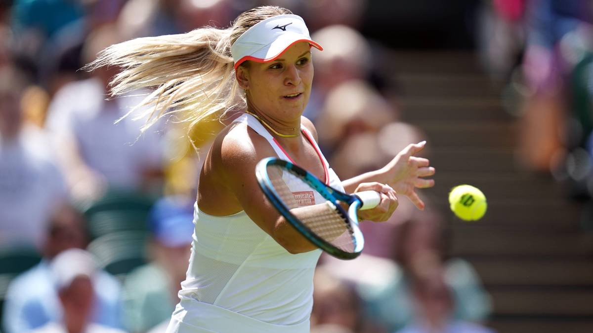 Tenisistka podczas meczu, w akcji uderza piłkę rakietą.