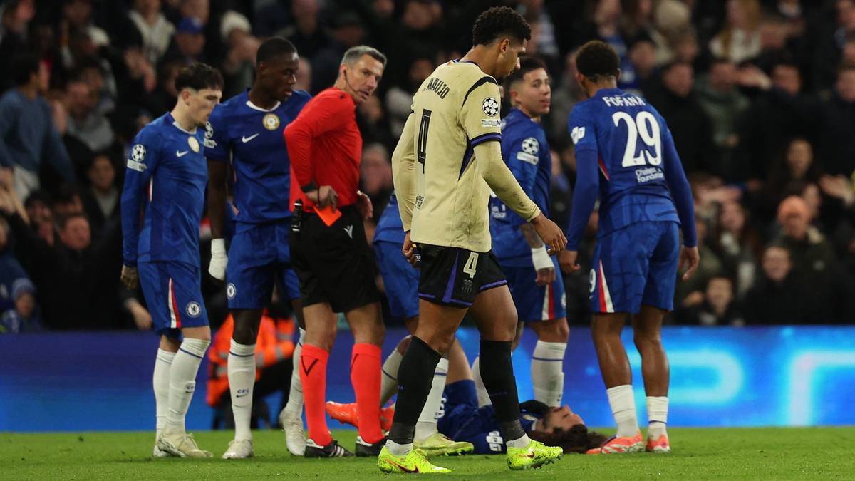 Piłkarze w niebieskich strojach otaczają leżącego zawodnika w żółtej koszulce.