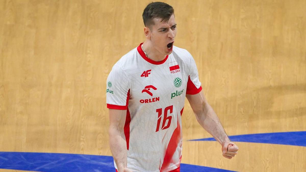 Młody siatkarz w białej koszulce z czerwonymi elementami, w białych spodenkach, krzyczy z zaciśniętą pięścią, z numerem 16 na koszulce.