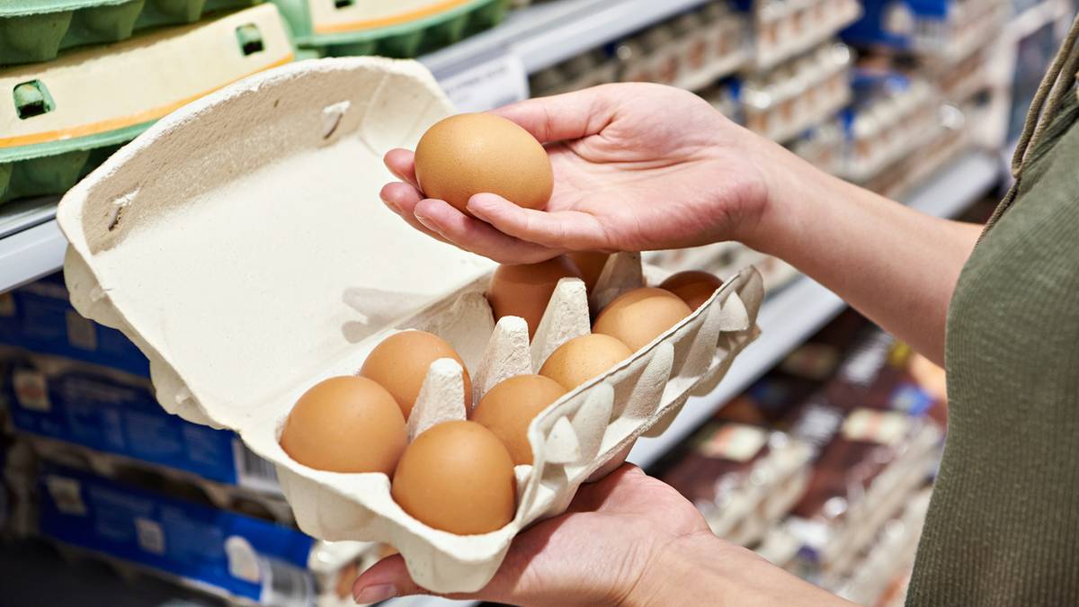 Dłoń klienta wybierająca jajko z wytłaczanki w sklepie.