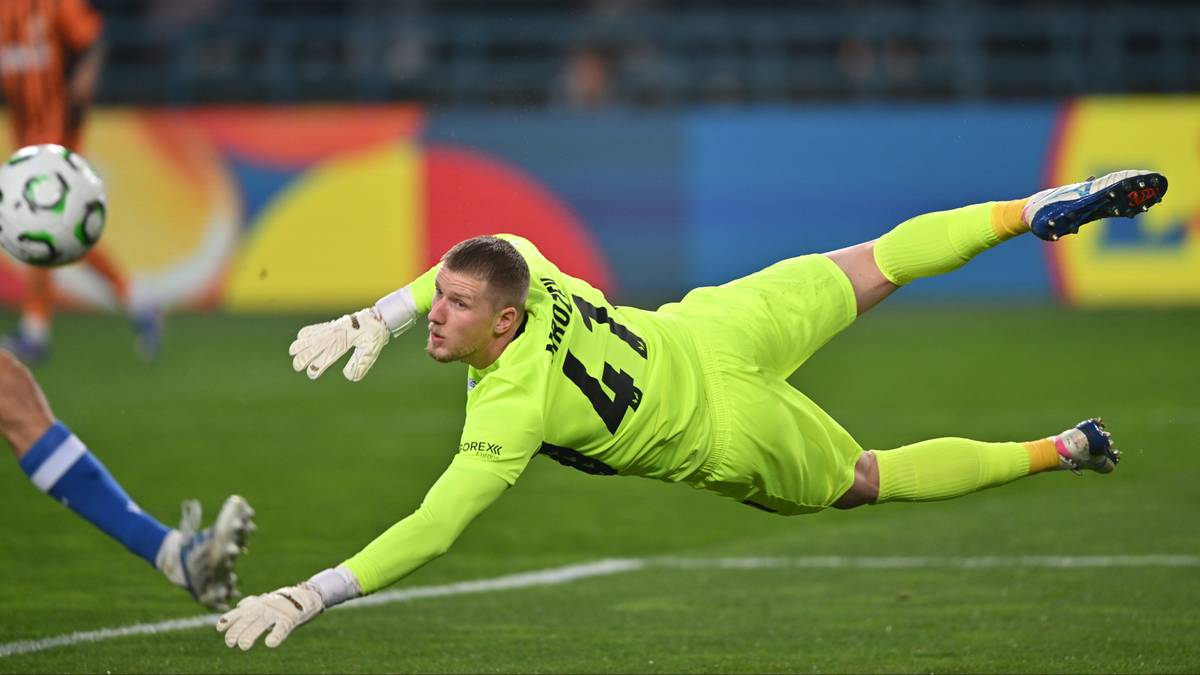 Bramkarz w żółtym stroju wykonuje rzut do obrony piłki nożnej.