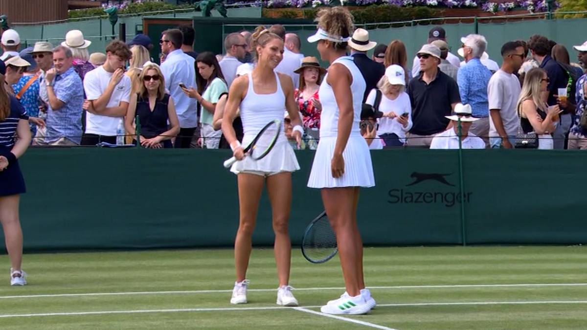 Dwie tenisistki w białych strojach stoją na korcie tenisowym, trzymając rakiety.