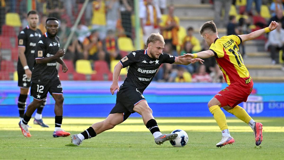 Dwóch piłkarzy rywalizuje o piłkę na boisku podczas meczu.