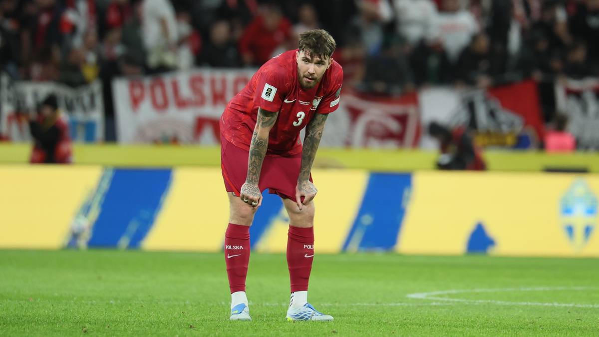 Piłkarz reprezentacji Polski w czerwonej koszulce, pochylony na boisku piłkarskim po meczu.