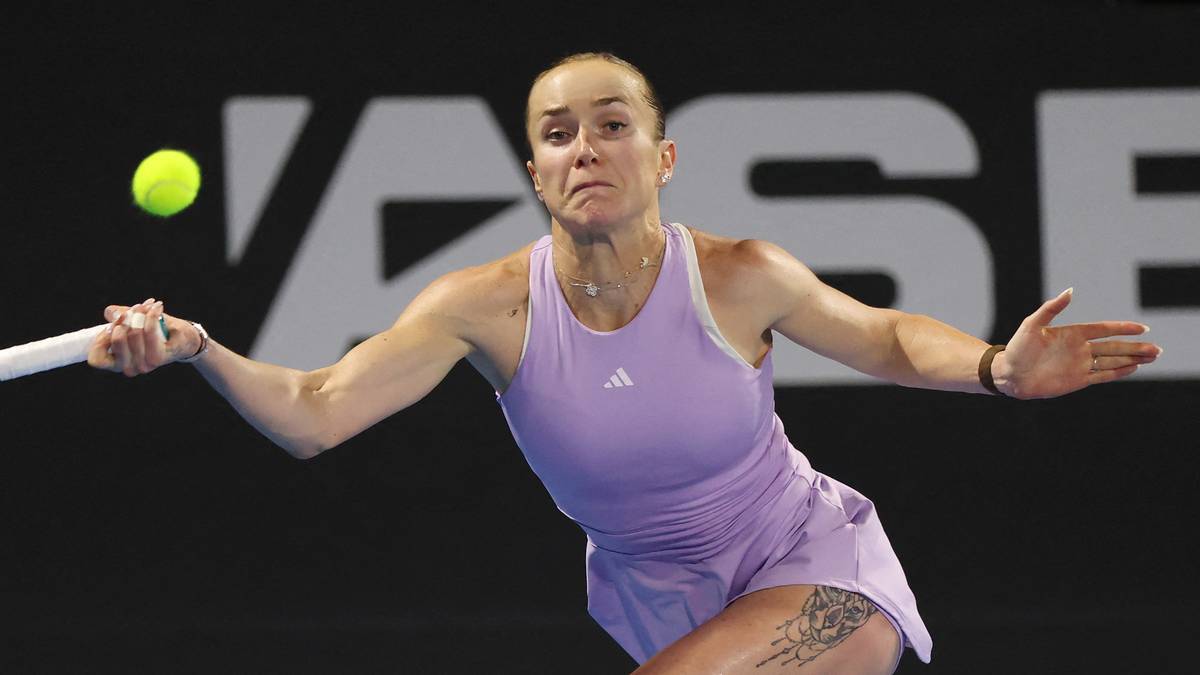 Tenisistka w lawendowym stroju sportowym uderza piłkę rakietą podczas meczu na korcie.