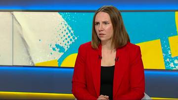 Anna Bryłka w czerwonej marynarce siedzi i patrzy w bok z zaniepokojoną miną.