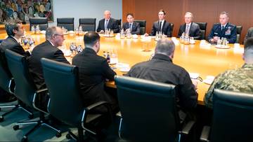 Grupa mężczyzn siedzi przy stole konferencyjnym podczas spotkania.