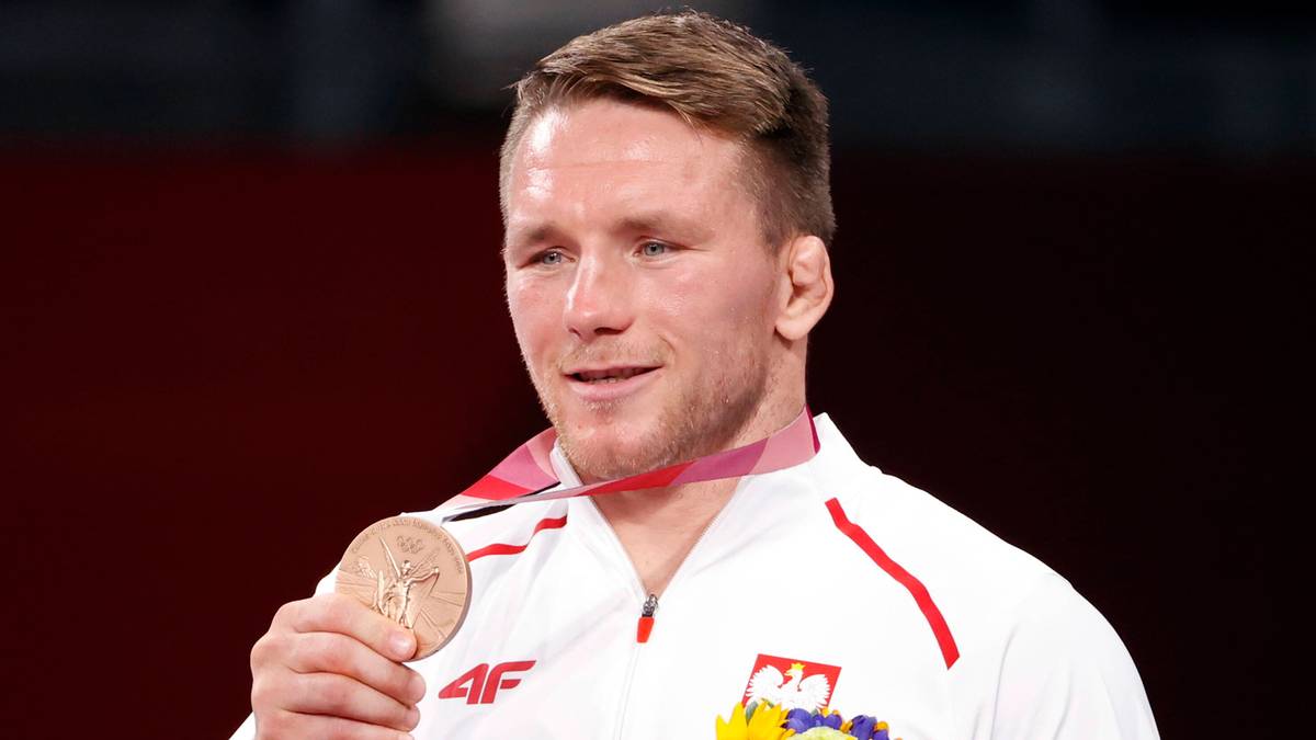 Zapaśnik Tadeusz Michalik prezentuje medal i bukiet słoneczników.