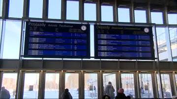 Tablice informacyjne na dworcu kolejowym: z lewej tablica "Przyjazdy", z prawej tablica "Odjazdy". Na obu tablicach widnieją liczne wpisy z nazwami miejscowości, numerami pociąg&oacute;w i godzinami, a także informacje o op&oacute;źnieniach i odwołaniach. W tle widać dużą przeszkloną ścianę dworca.