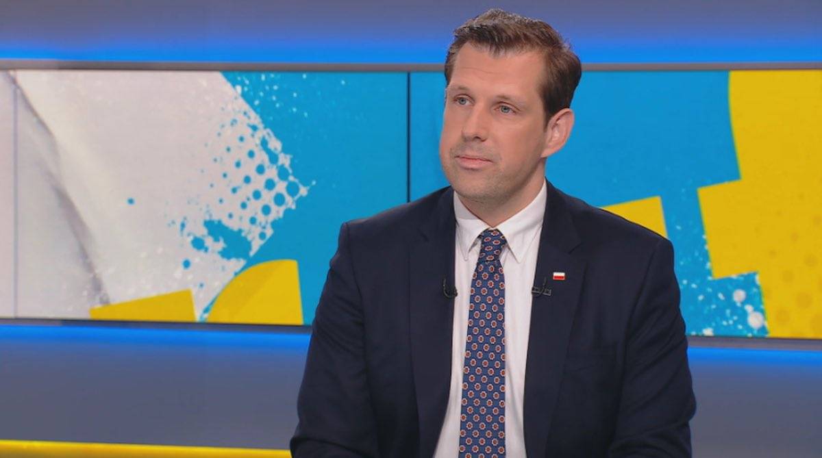 Marcin Fijołek w garniturze i krawacie podczas wywiadu.