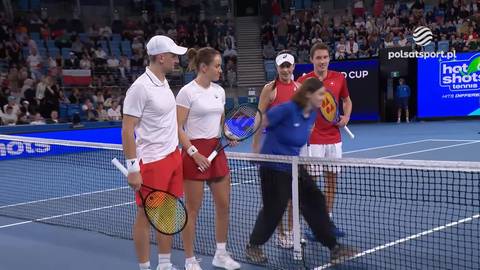 Cztery osoby stoją na korcie tenisowym po meczu, uśmiechając się. Dwie kobiety i dwaj mężczyźni pozują do zdjęcia.