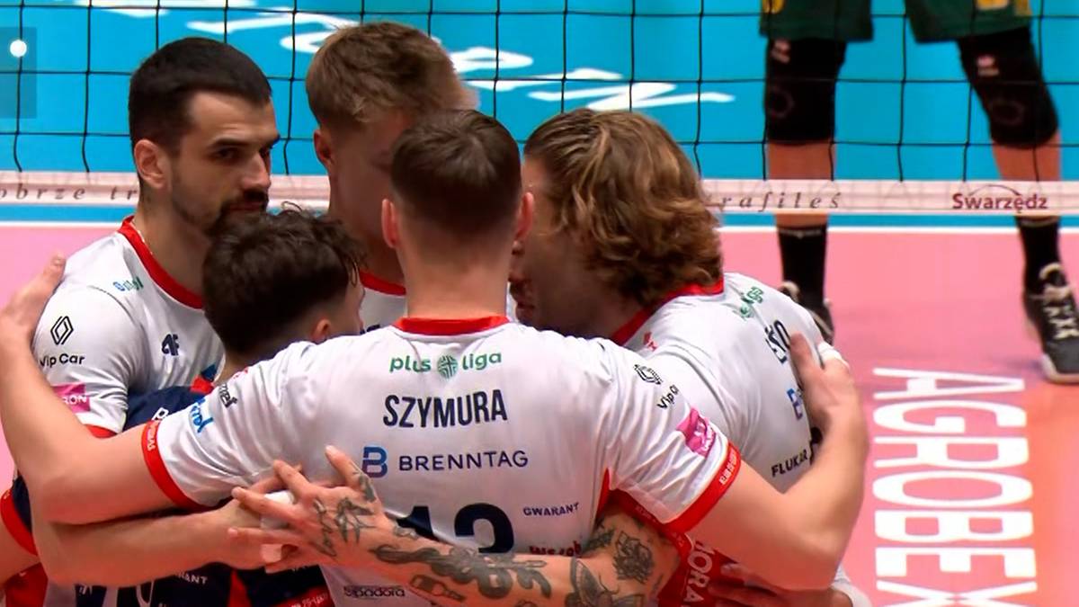 Siatkarze w białych koszulkach obejmują się w geście radości, z widocznymi nazwiskami i numerami na strojach.