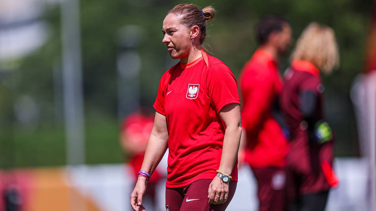 Kobieta w czerwonej koszulce z godłem Polski, patrzy w bok z profilu. Nosi zegarek na lewym nadgarstku.