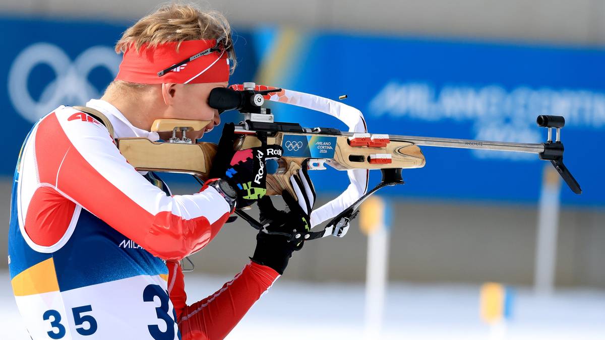 Biathlonista celuje z karabinu podczas zawod&oacute;w, ubrany w biało-czerwony str&oacute;j sportowy z numerem 35.