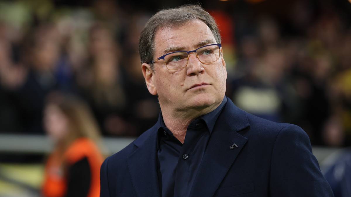 Portret Michała Probierza, trenera piłkarskiej reprezentacji Polski, w okularach i ciemnym stroju, patrzącego w bok.