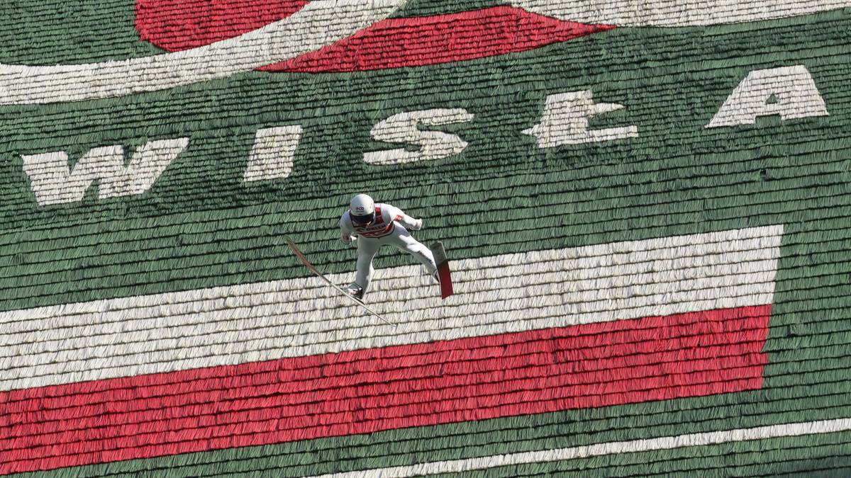 Skoczek narciarski w locie na tle skoczni z napisem "WISŁA"