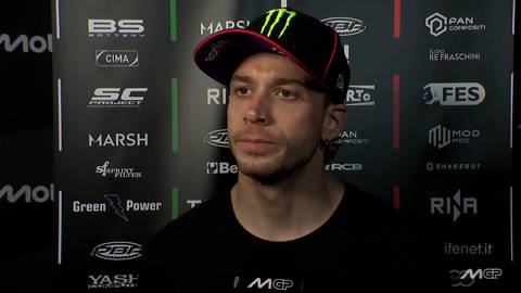 Marco Bezzecchi, zawodnik MotoGP, w czapce z daszkiem z logo Monster Energy, na tle ściany z logotypami sponsor&oacute;w.
