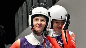 Dwie kobiety w kaskach saneczkarskich, jedna z nich patrzy w stronę obiektywu.