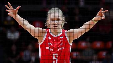 Siatkarka w czerwonej koszulce z numerem 5 na plecach wykonuje gest rękami nad siatką.