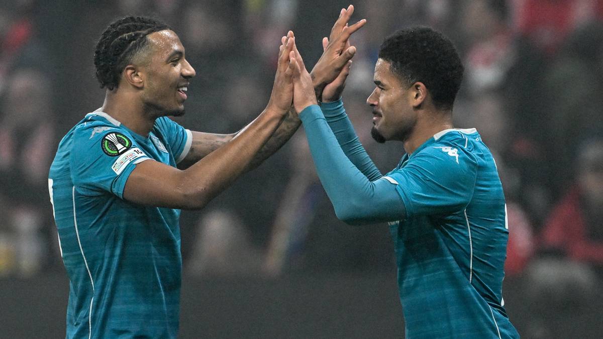 Dw&oacute;ch piłkarzy w niebieskich strojach z logo Ligi Konferencji Europy daje sobie piątkę.