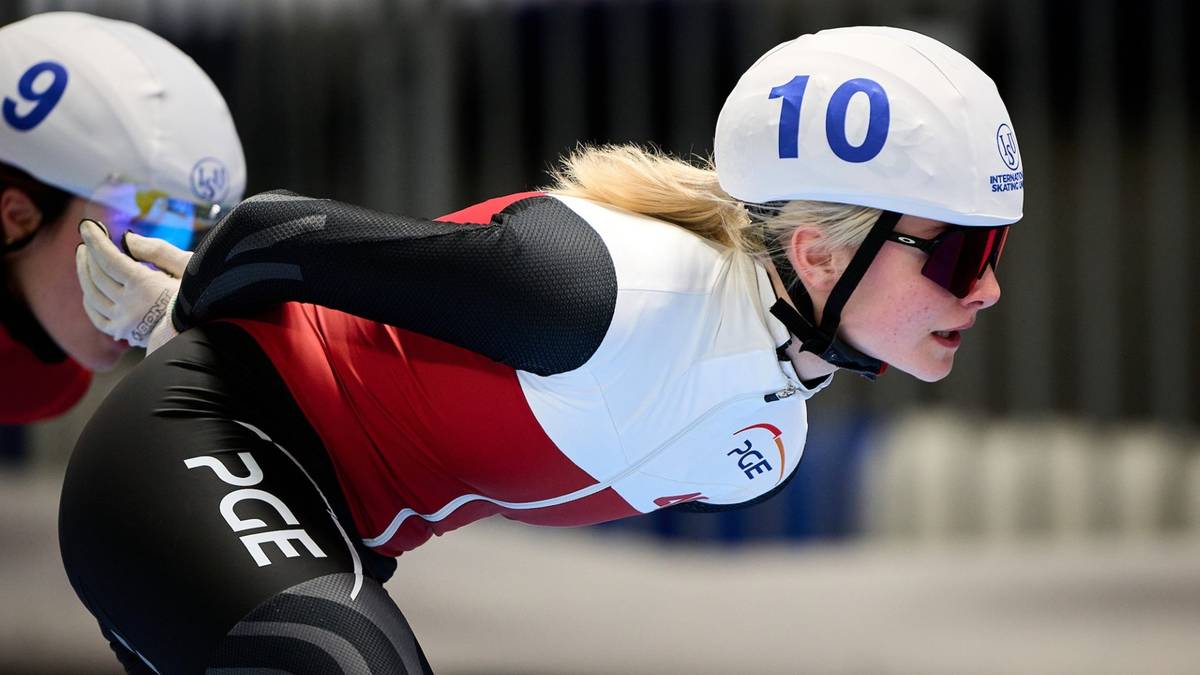 Dwie juniorki w strojach panczenowych i kaskach podczas zawodów, jedna z numerem 10 na kasku jest w ruchu.