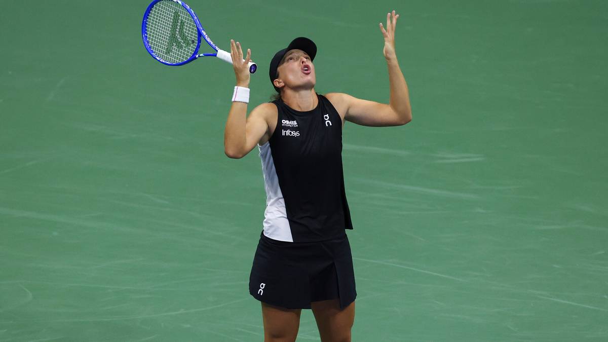 Iga Świątek, tenisistka, unosi ręce w geście triumfu, trzymając rakietę tenisową.