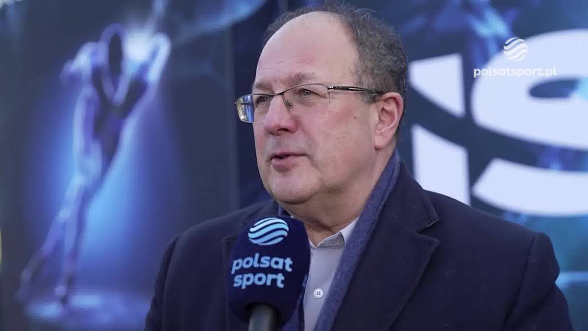 Marian Kmita w okularach i marynarce, trzymający mikrofon Polsat Sport podczas wywiadu.