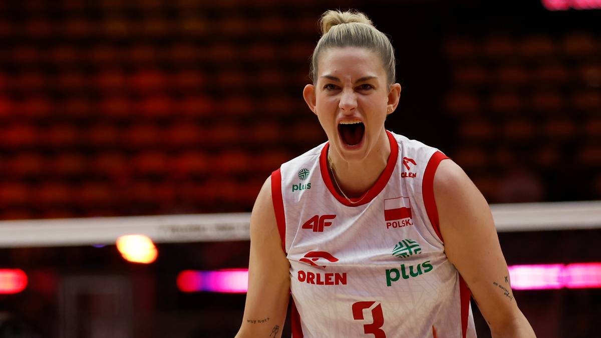 Siatkarka w białej koszulce z czerwonymi detalami, z numerem 3, otwiera usta w okrzyku radości lub wysiłku.