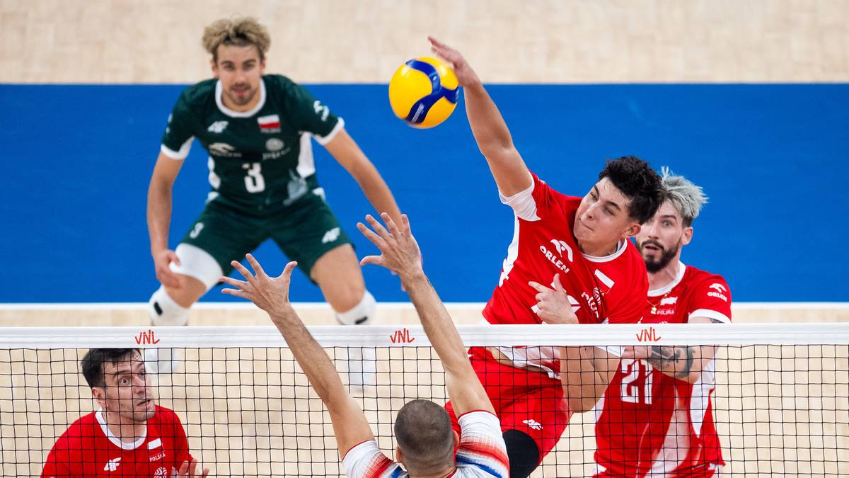 Siatkarze rywalizujący przy siatce podczas meczu, jeden z graczy w białym stroju z numerem 30 atakuje piłkę.