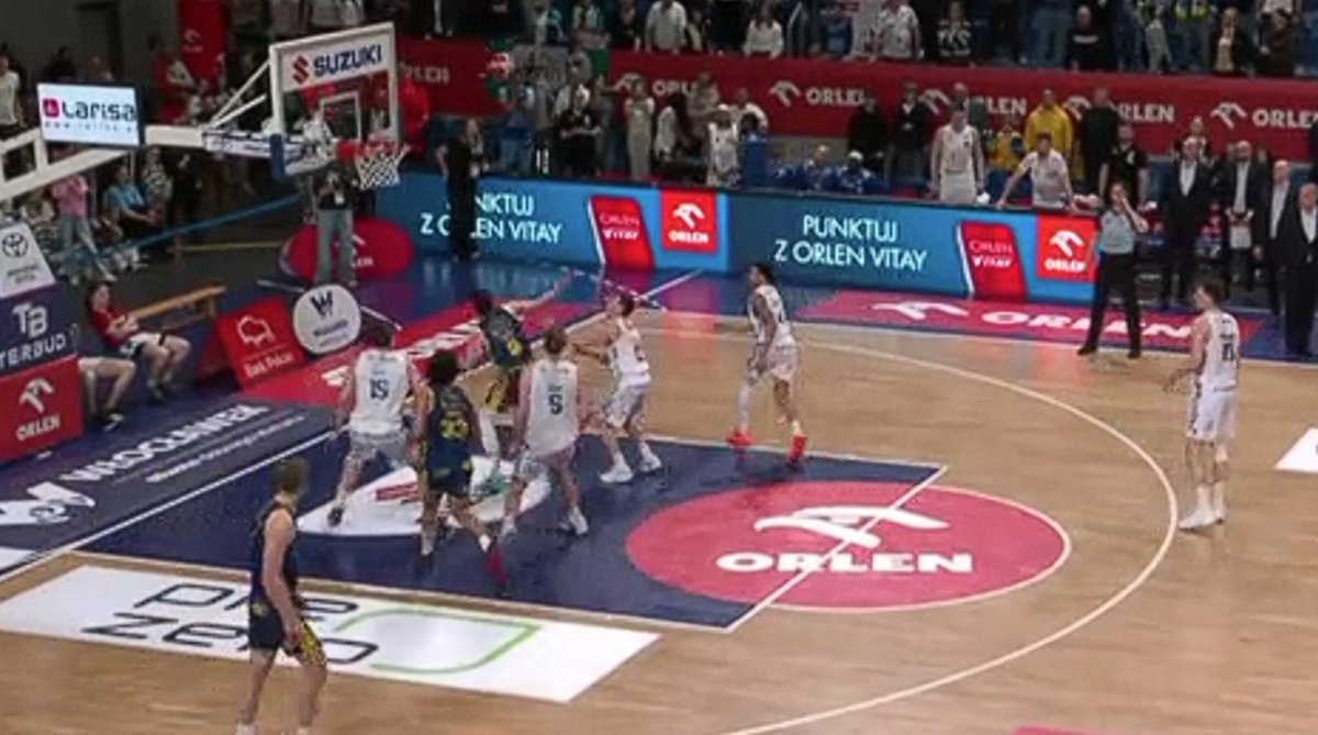 Gracze drużyny koszykarskiej wykonują akcję pod koszem, pr&oacute;bując zdobyć punkty.