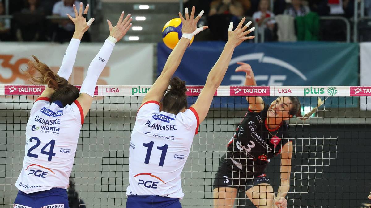 Trzy zawodniczki siatkówki rywalizują przy siatce podczas meczu.