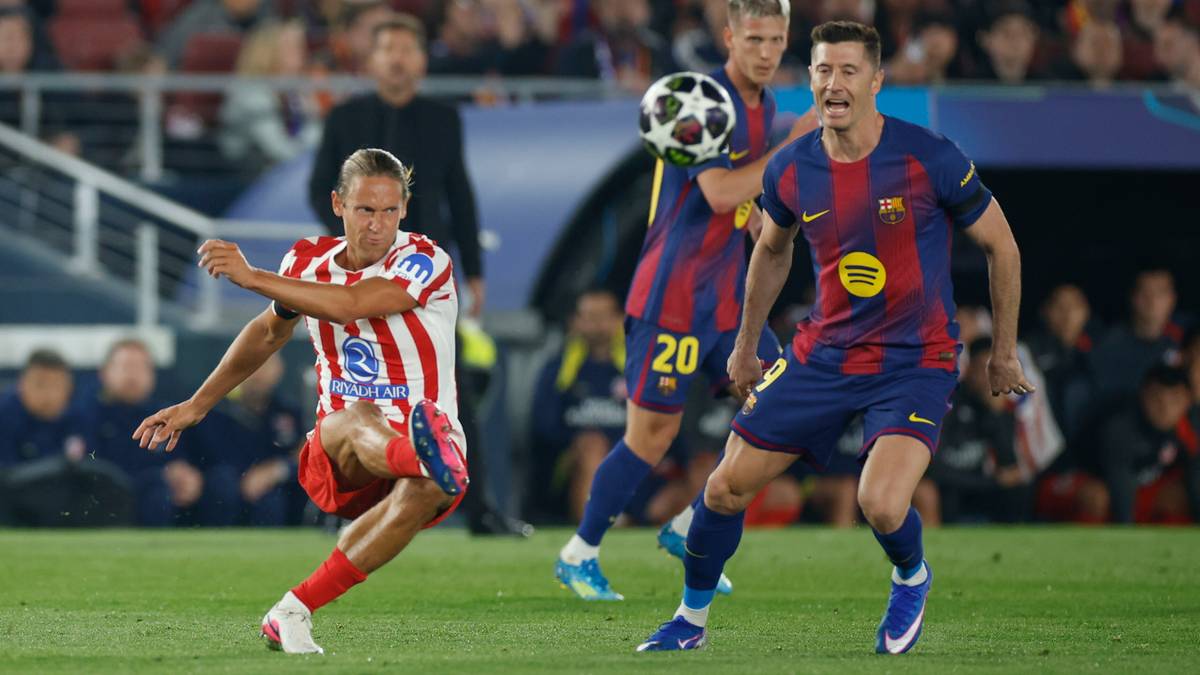 Dw&oacute;ch piłkarzy podczas meczu, jeden w stroju Atletico Madryt, drugi w stroju FC Barcelony, walczy o piłkę na boisku.