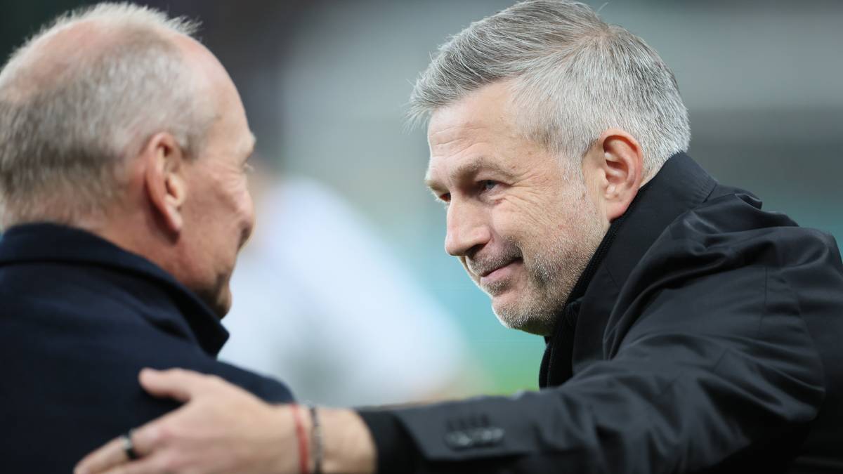 Dwóch mężczyzn w garniturach, prawdopodobnie trenerzy piłkarscy, w interakcji.