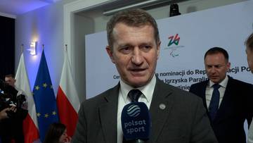 Ireneusz Raś w garniturze, z mikrofonem Polsat Sport, udziela wywiadu na tle polskich flag i logotyp&oacute;w.