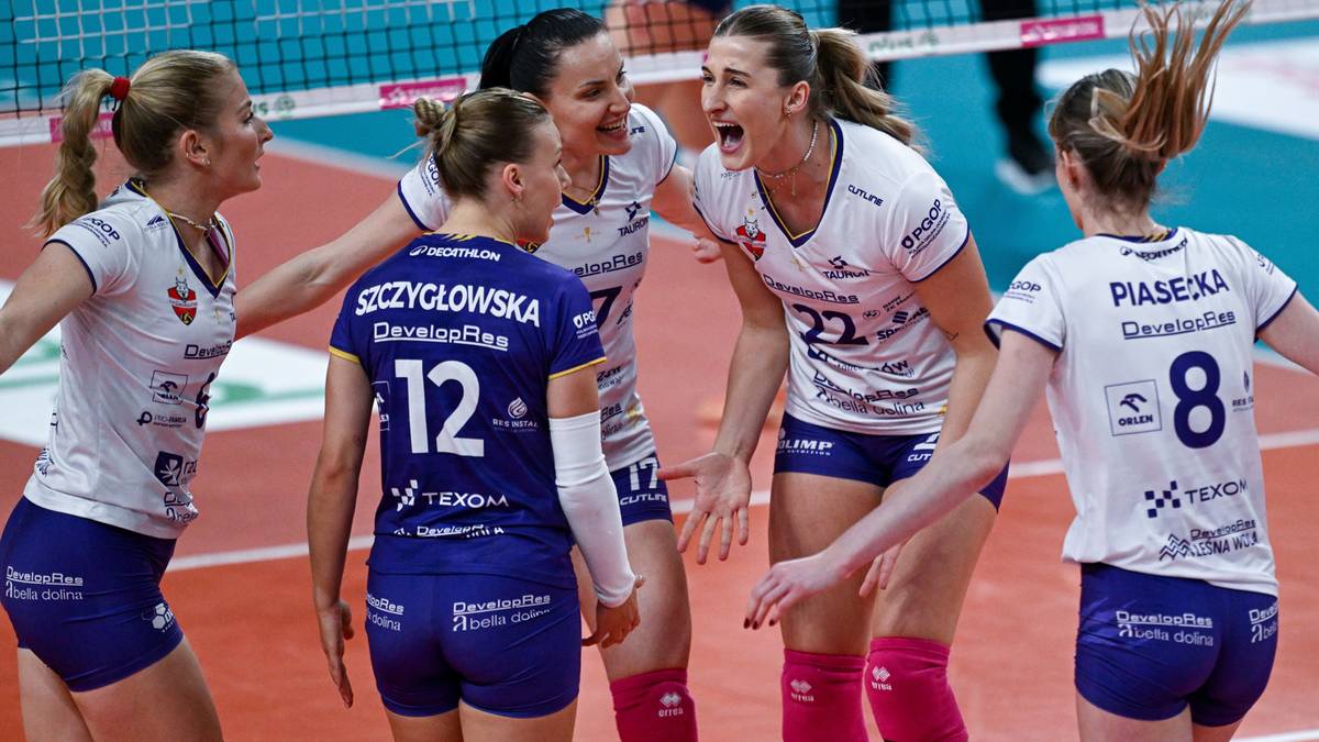 Grupa siatkarek świętuje na boisku, jedna z nich, Aleksandra Szczygłowska (nr 12), uśmiecha się do koleżanek.