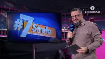 Mężczyzna z mikrofonem i kartką obok ekranu z napisem "#7 Strefa".