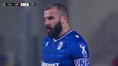 Piłkarz Mikael Ishak w niebieskiej koszulce z białymi elementami, z charakterystyczną brodą, w trakcie meczu.