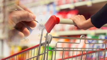 Zbliżenie na w&oacute;zek sklepowy w supermarkecie. W tle dłoń z oł&oacute;wkiem zaznacza daty na kalendarzu.