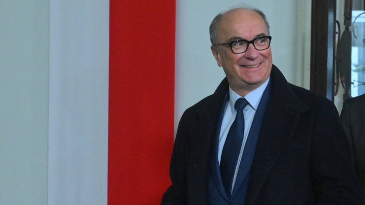 Mężczyzna w eleganckim stroju, w okularach, uśmiecha się.