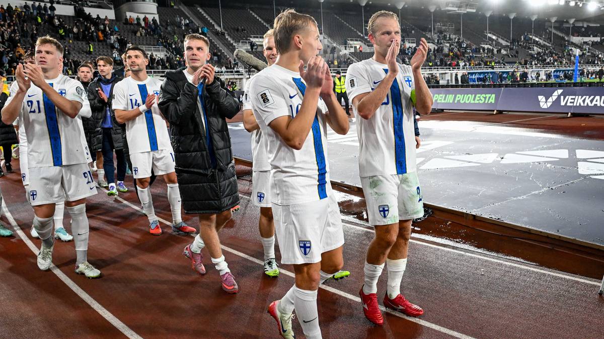 Piłkarze w białych strojach świętują na boisku, część z nich klaszcze.