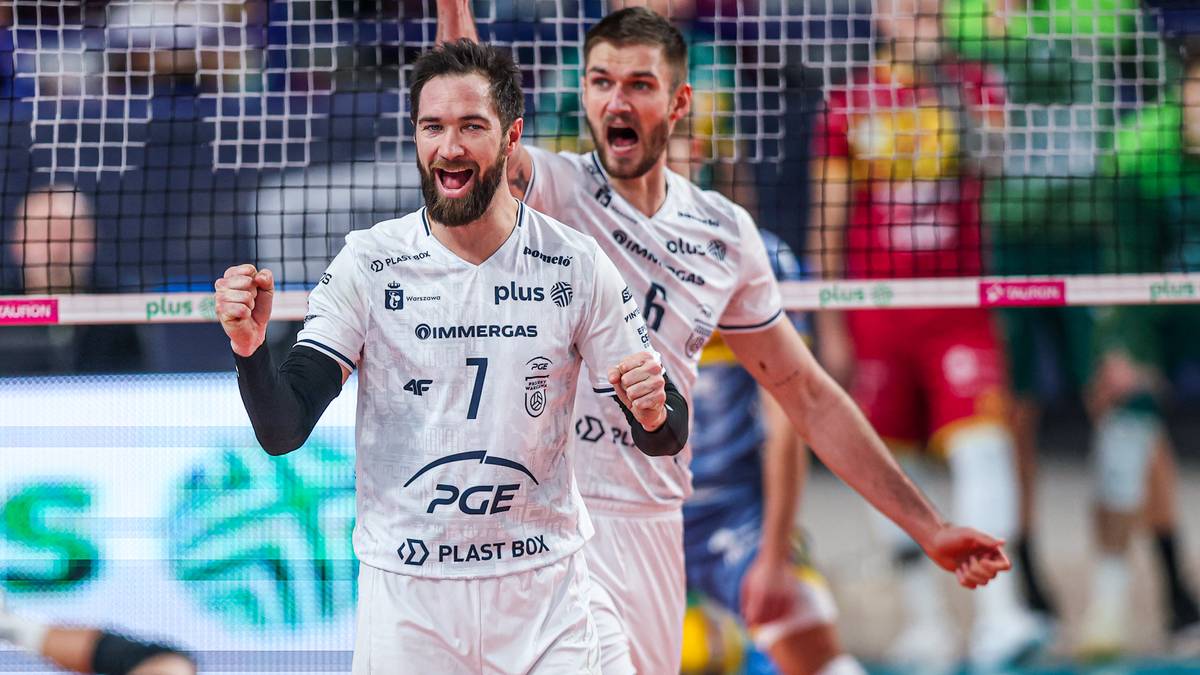 Dw&oacute;ch siatkarzy w białych koszulkach z numerami 7 i 6 świętuje punkt, obaj uśmiechnięci, z uniesionymi rękami.