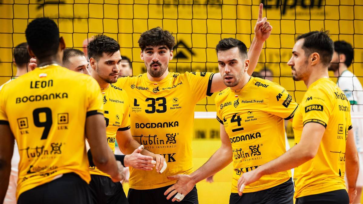 Siatkarze w ż&oacute;łtych strojach świętują coś na boisku.