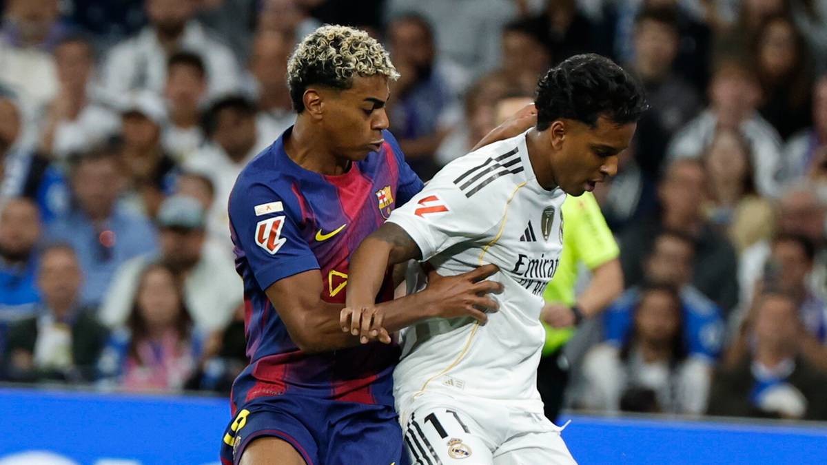 Piłkarz FC Barcelony w niebiesko-czerwonym stroju powala piłkarza Realu Madryt w białej koszulce.